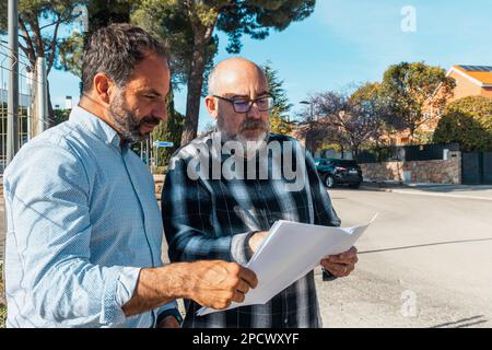 two men standing next to each other looking at papers. Teamwork concept Stock Photo