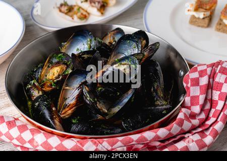 Baked blue mussels in spicy with lemon in a black cast-iron pot Stock Photo