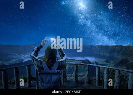 Woman with a smartphone under a starry night sky Stock Photo