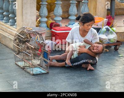 Phnom Penh,Cambodia-December 23 2023:A Khmer woman,selling small caged birds to Khmers,to set free after making a wish for their families,eases her wa Stock Photo