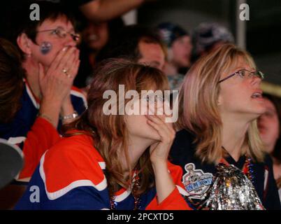 Edmonton Oilers fans Deanna McCullough, center, and Shelly Sych, right,  watch from Edmonton's Rexall Place as their team loses 3-1 to the Carolina  Hurricanes in Raleigh, N.C. during Game 7 of the