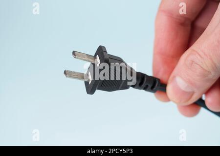 Electrical american plug in hand on blue background Stock Photo