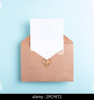 Top view of empty card in kraft envelope on pastel blue background. Place for text. Stock Photo