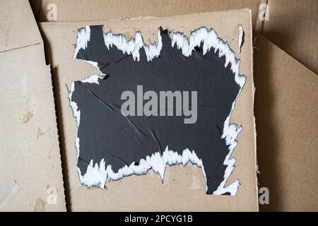 Ripped black square paper on cardboard background Stock Photo