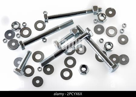 Bolts, nuts, screws and washers scattered on white background in top view Stock Photo