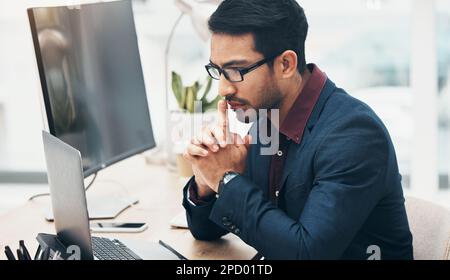 Office, brainstorming and man at computer thinking of ideas for online project with serious concentration. Planning, analytics and Indian businessman Stock Photo