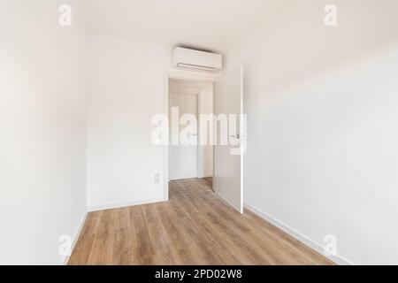 View of the front door to a small white air-conditioned room with wooden floor in a hotel. Concept of simple renovation or an empty apartment after Stock Photo