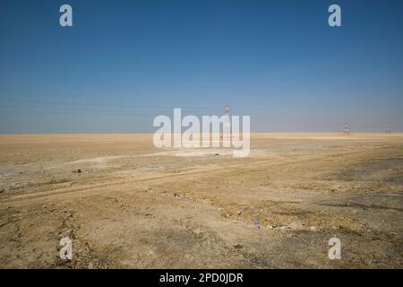Electric power transmission lines strung between metal support towers in the desolate, empty desert. Off the E11 highway outside Abu Dhabi, UAE, Unite Stock Photo