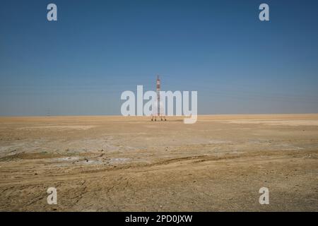 Electric power transmission lines strung between metal support towers in the desolate, empty desert. Off the E11 highway outside Abu Dhabi, UAE, Unite Stock Photo