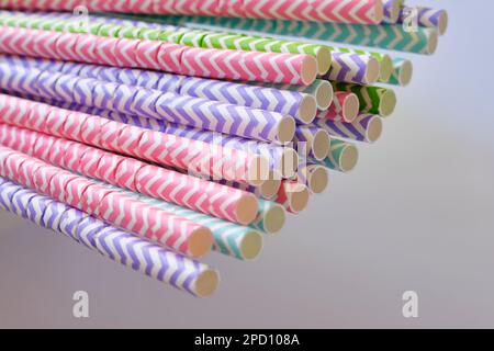 Closeup of colorful striped paper straws in front of a grey background. Environmentally friendly concept with selective focus. Stock Photo