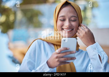Smiling young Muslim female entrepreneur wearing a hijab sitting in her ...