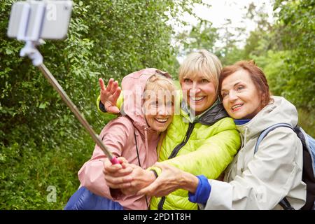 Happy senior woman taking selfie with smartphone on hiking trip in nature Stock Photo