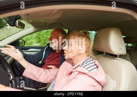 Angry elderly man and woman gesturing while talking in car during road trip Stock Photo
