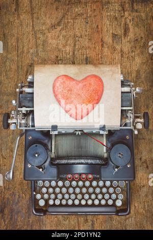 Top view of a vintage typewriter with red heart on a sheet of paper Stock Photo