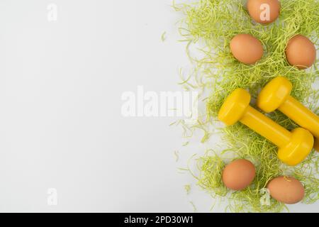 Dumbbells and Easter eggs. Healthy fitness lifestyle composition, gym workout, sport nutrition concept. Fit flat lay with copy space. Stock Photo