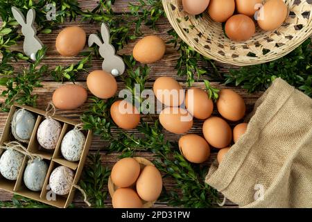Easter eggs, boxwood branches and bunnies decorations. Egg hunt concept. Flat lay food composition for Easter or Pascha celebration. Stock Photo