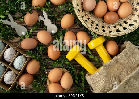 Gym dumbbells, Easter eggs, boxwood branches and bunny decorations. Healthy diet choice concept. Fitness workout, sport training flat lay composition. Stock Photo