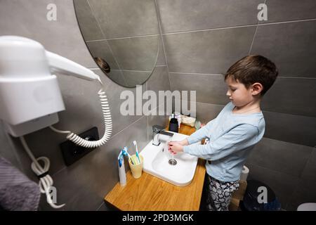 Boy washes hands in the sink at bathroom. Stock Photo