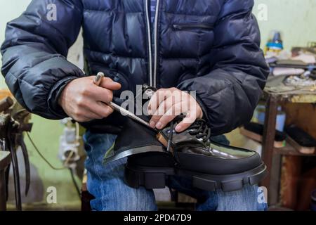 Master taking care of shoes in his workshop where he repairing them Stock Photo