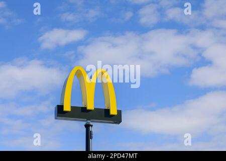 McDonald's logo against blue sky and white fair weather clouds at McDonald's restaurant in Salo, Finland. March 12, 2023. Stock Photo