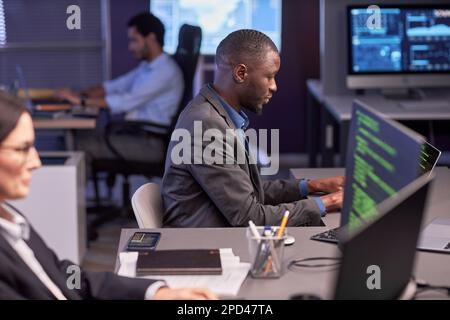 Side view portrait of black businessman using computer in high tech IT security office Stock Photo
