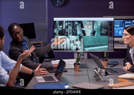 Group of people discussing security camera footage in meeting Stock Photo