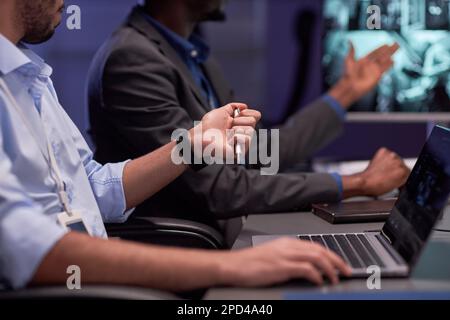 Close up of man using laptop in meeting at security agency Stock Photo