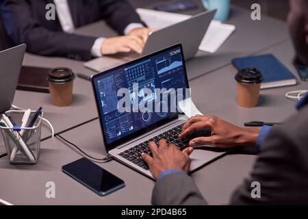 Close up of unrecognizable black businessman using laptop with high tech data charts Stock Photo