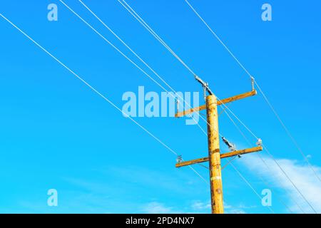 Wooden power pole with wires against a clear blue sky. Energy, power supply, technology and engineering background. Stock Photo