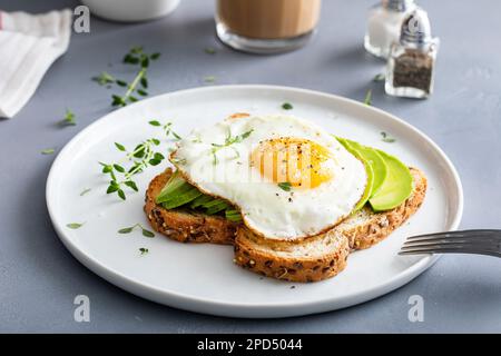 Wholegrain avocado toast with fried egg on top, healthy breakfast idea Stock Photo