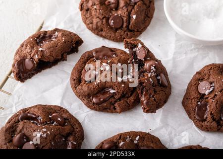 Double chocolate cookies with chocolate chips and flaky salt on a cooling rack Stock Photo