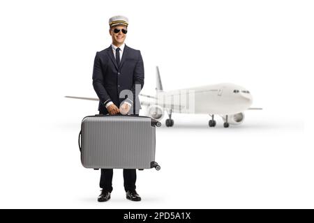Pilot carrying a suitcase and and standing in front of an aircraft isolated on white background Stock Photo