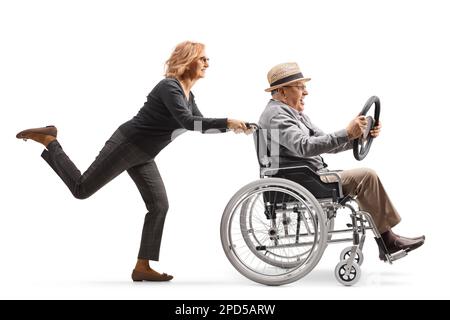 Woman pushing a mature man in a wheelchair holding a steering wheel isolated on white background Stock Photo