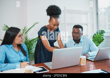 Three colleagues concentrate on reports in business meeting, looking at screen Stock Photo