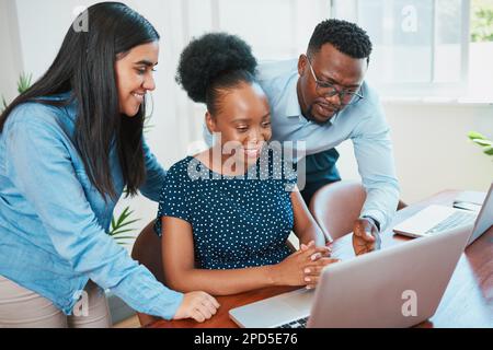 Three diverse colleagues discuss and laugh around laptop in office Stock Photo