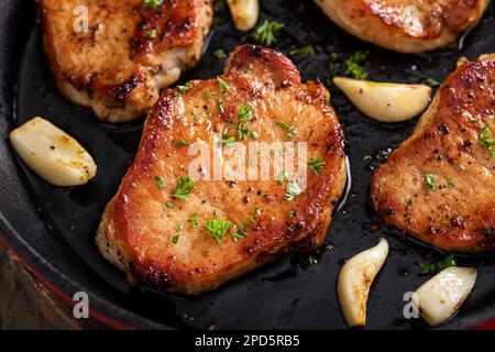 Pork chops cooked with garlic in a cast iron pan Stock Photo