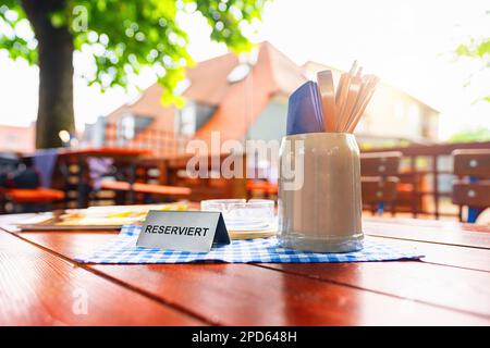 german beer garden table with reserved table sign with places setting at summer Stock Photo