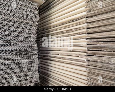 Closeup of the cardboard pile for packing parcels to send to customers is laying near the warehouse wall, front view with the copy space. Stock Photo