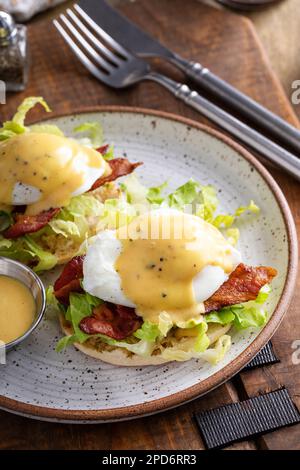 Eggs Benedict with bacon and lettuce on english muffins with hollandaise, traditional breakfast idea Stock Photo