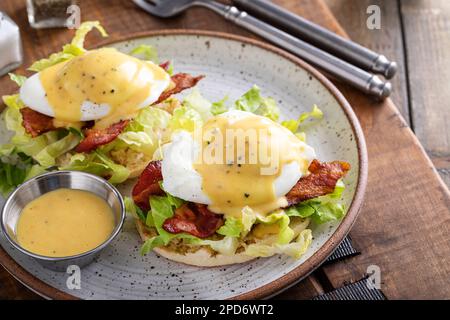 Eggs Benedict with bacon and lettuce on english muffins with hollandaise, traditional breakfast idea Stock Photo