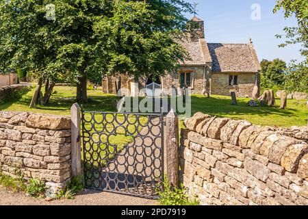 The church of St. James in the Cotswold village of Clapton-on-on-the-Hill, Gloucestershire UK. The wrought iron horseshoe gate was made locally. Stock Photo