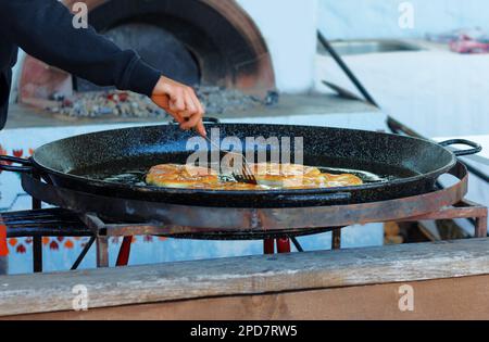 Cook roasts flour pastries in a large pan with butter outdoor Stock Photo