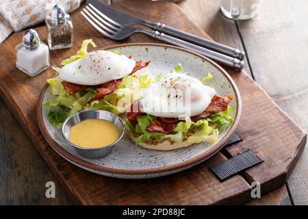 Eggs Benedict with bacon and lettuce on english muffins Stock Photo