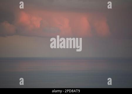 rainstorm highlighted by red light from setting sun at dusk over the ocean Lanzarote, Canary Islands, Spain Stock Photo