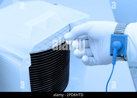 A batch of silicon wafers packed in a plastic storage box in the clean room of a semiconductor foundry ready for microchip production. Stock Photo