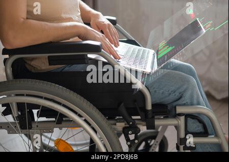 Caucasian woman in a wheelchair works at a laptop. HUD menu. Stock charts. brokerage terminal. Stock Photo