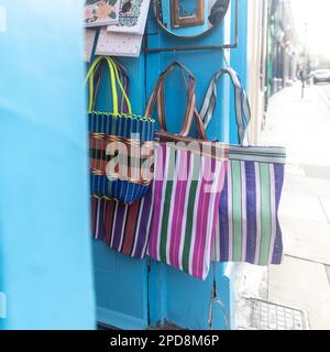 Multi-colored striped seventies-style bags hang on the store door. Stock Photo