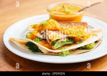 Plate with vegan broccoli quesadillas, served with an apricot-carrot sauce.