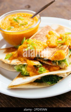 Plate with vegan broccoli quesadillas, served with an apricot-carrot sauce.