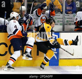 New York Islanders goalie Rick DiPietro, right, deflects the puck as the  Islanders' Joel Bouchard (4) and Boston Bruins' Wayne Primeau (20) battle  in the crease during the first period of NHL